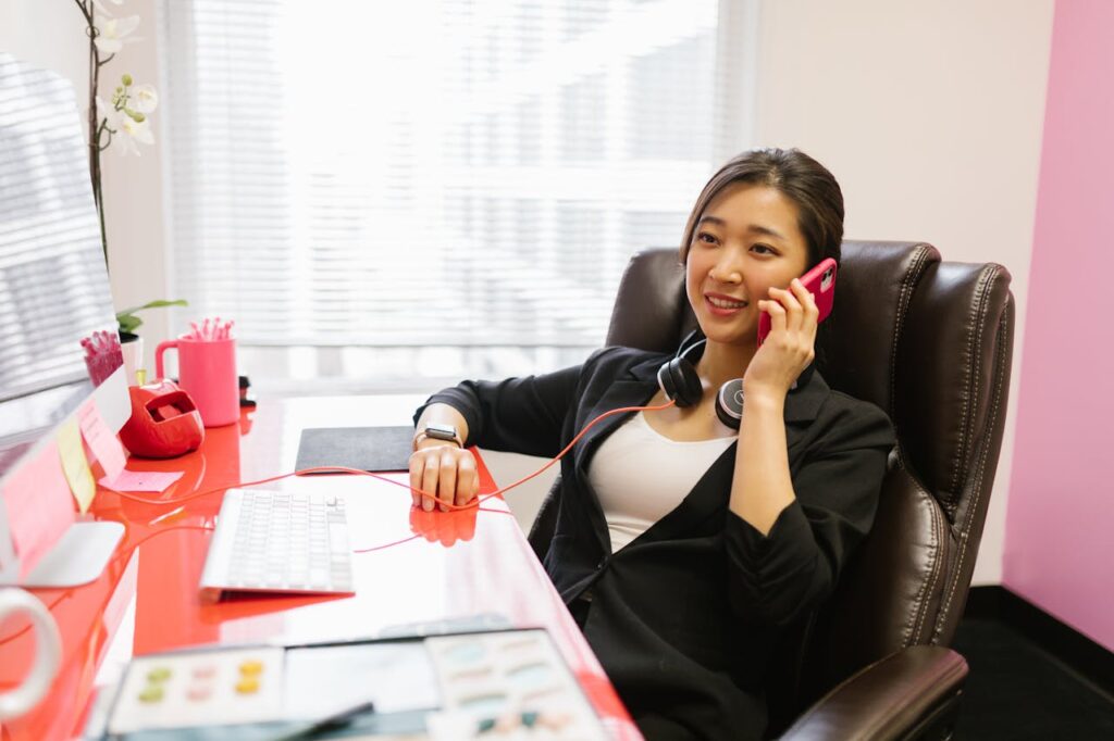 Asian woman working remotely from home office while on a phone call